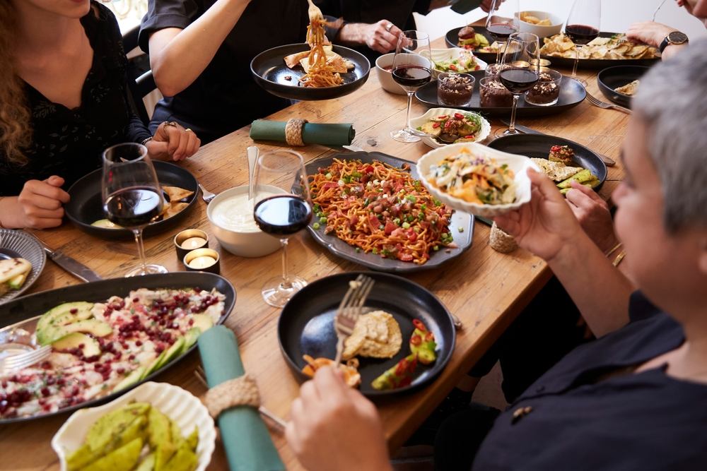 varias personas comen comida mediterránea alrededor de una mesa
