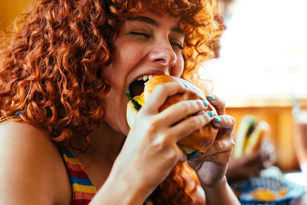 mujer come una hamburguesa y la disfruta